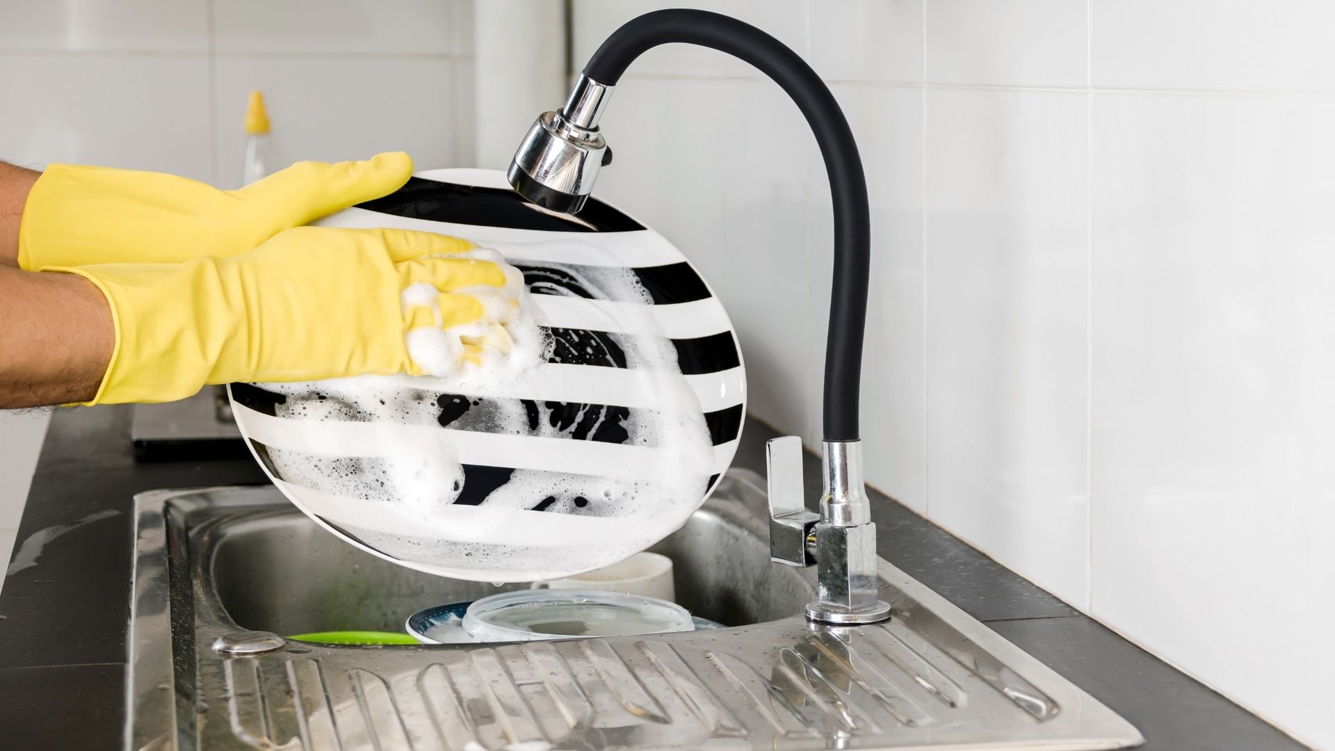 A person washing dishes with running water