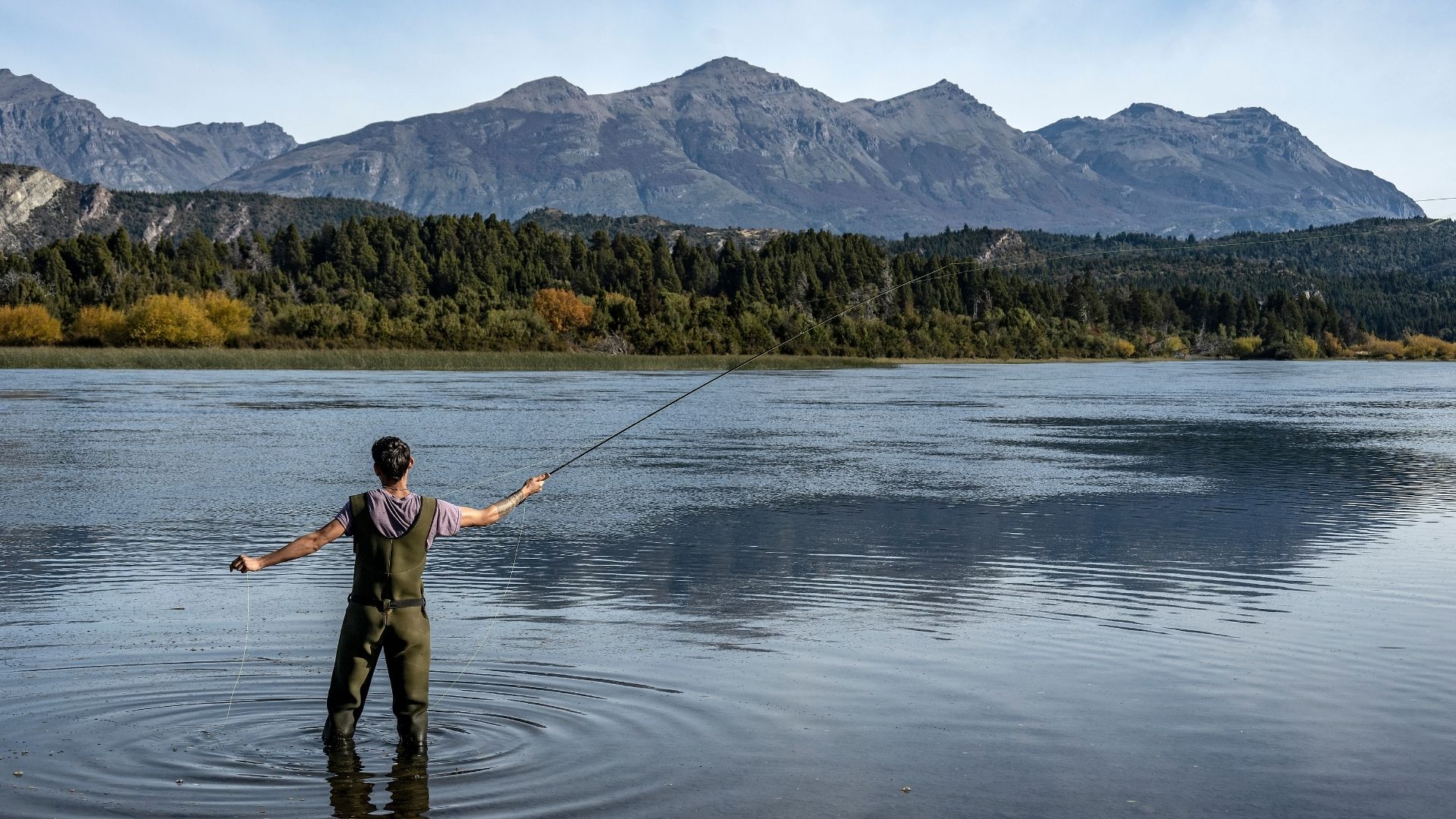 An angler fishing at a serene lake, tracking their time using the Fishing Time Cost Calculator